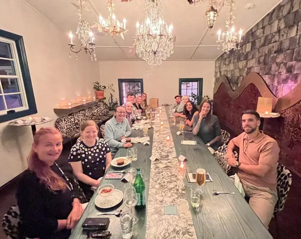 Group of people gathered around a long dining table for dinner and drinks